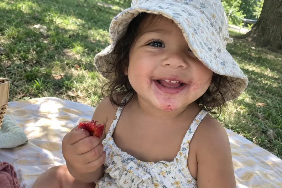 Maya eating strawberries at a summer picnic, shared with grandparents in the family journal